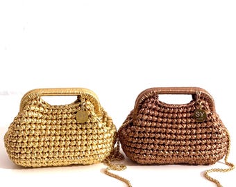 Può includere: Due borse a mano all'uncinetto in oro e bronzo. Ogni borsa ha una struttura strutturata, un manico superiore e una tracolla a catena dorata. Una piccola etichetta rotonda con le iniziali "SY" pende da ogni borsa. Su sfondo bianco.