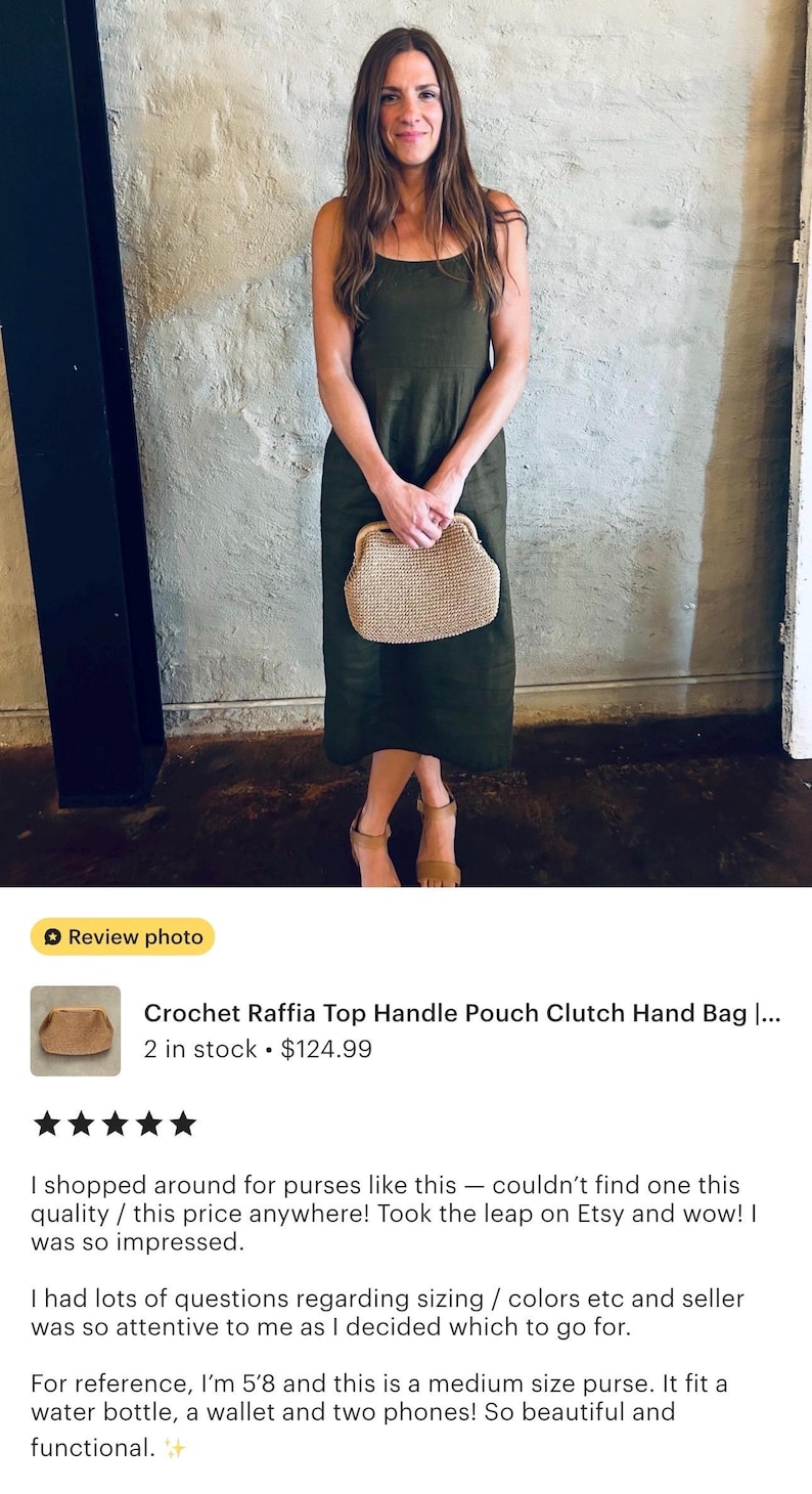 May include: A woman wearing a dark green dress holds a beige crochet raffia top handle pouch clutch hand bag. The bag is a medium size and can fit a water bottle, a wallet, and two phones.
