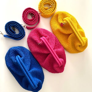 Pu&ograve; includere: Tre borse all'uncinetto in blu, rosa e giallo con tracolle abbinate. Le borse sono realizzate con una trama testurizzata e aperta e hanno una forma arrotondata leggermente cascante.