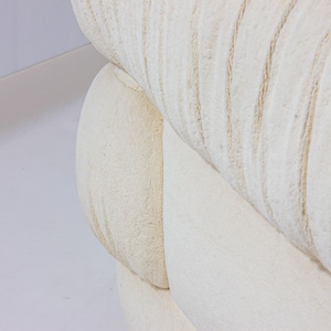 May include: Close-up of a section of a cream-coloured, textured sofa. The fabric has a ribbed pattern with subtle variations in tone. The design suggests a focus on comfort and a neutral aesthetic, suitable for various interior styles.