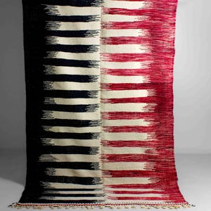 May include: A handwoven rug with a striped pattern in black, white and red. The rug has a fringe border.