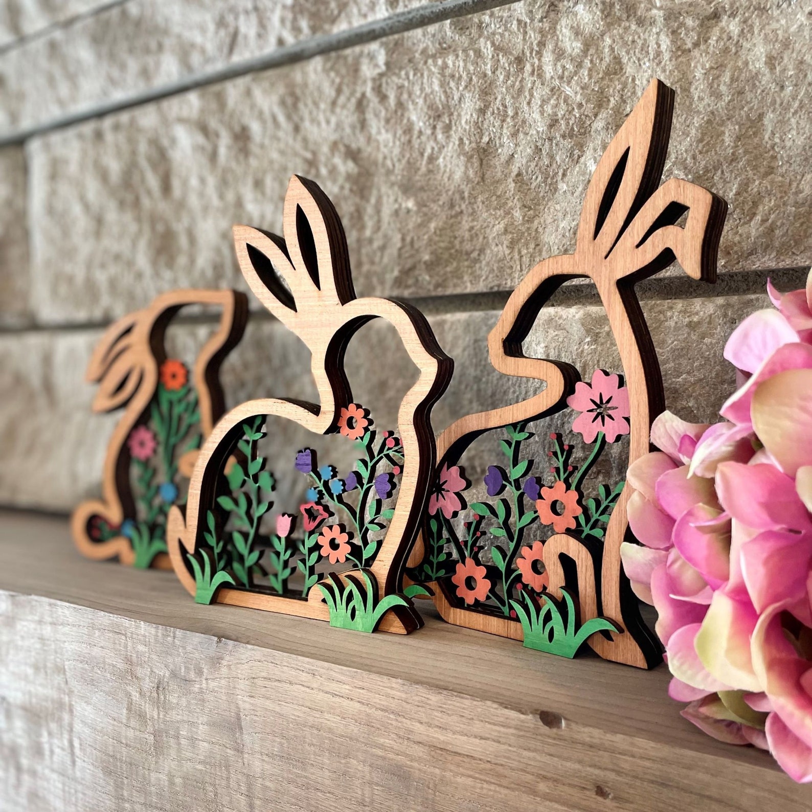 Three wooden cut out bunnies on a shelf