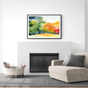 May include: A watercolor painting of a forest scene with green, yellow, orange, and red trees. The painting is framed in black and hanging above a fireplace in a living room.