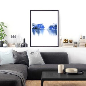 Op de afbeelding: Een ingelijst aquarel schilderij van een blauw landschap met een reflectie in het water. Het schilderij is op een witte achtergrond en is ingelijst in zwart.