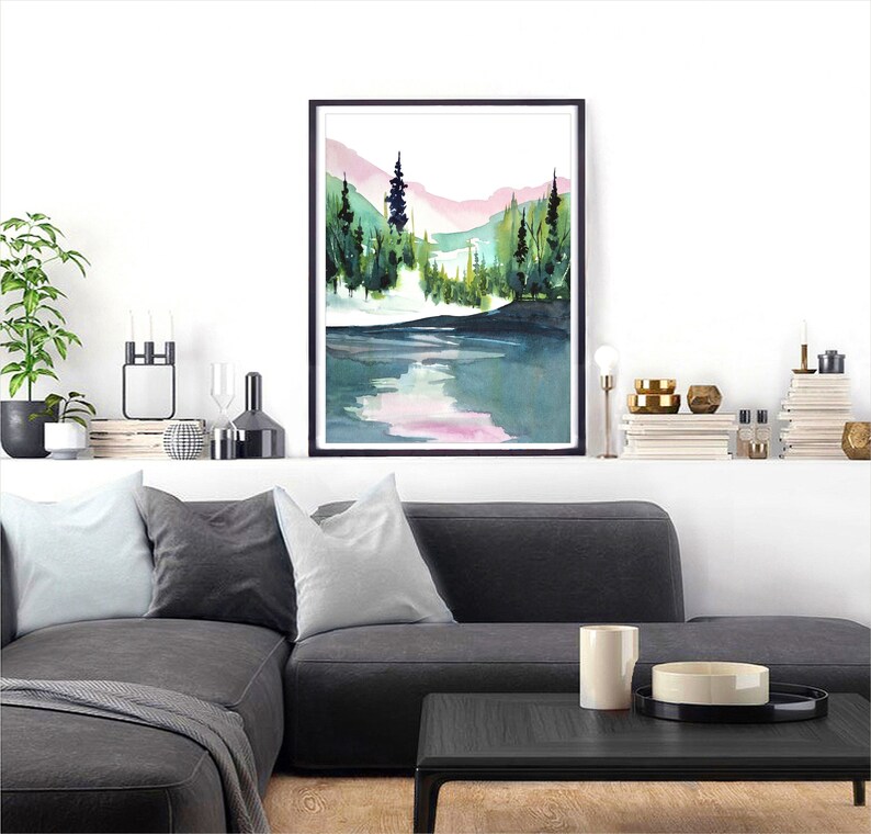 Pode incluir: Pintura em aquarela de uma cena de floresta com um lago em primeiro plano. As &aacute;rvores s&atilde;o verdes e as montanhas ao fundo s&atilde;o rosa e azuis.