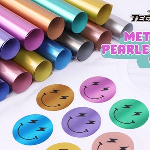 Può includere: Assortimento di rotoli di vinile perlato metallizzato in vari colori, tra cui oro, argento, blu, rosa e verde. Il vinile è mostrato su una maglietta bianca con un design a forma di faccina sorridente in diversi colori.