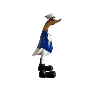 Könnte beinhalten: Eine hölzerne Entenfigur, die in Blau und Weiß bemalt ist und einen weißen Matrosenhut mit schwarzen Punkten und schwarze Stiefel trägt. Die Ente hat einen braunen Holz Hals und Kopf.