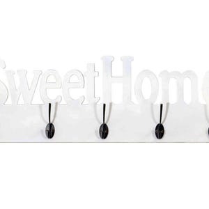 Könnte beinhalten: Eine weiße Wandgarderobe mit dem Schriftzug SweetHome in fetter Schriftart im oberen Bereich. Die rechteckige Basis verfügt über fünf gleichmäßig verteilte schwarze Metallhaken in Löffelform, die an der Vorderseite angebracht sind.
