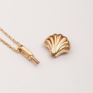 May include: A gold chain necklace with a small, detailed seashell pendant. The pendant is separate from the chain and can be attached with a screw.