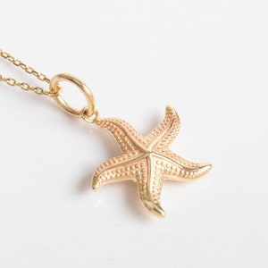 Pode incluir: Um colar de corrente de ouro com um pingente de estrela do mar detalhado. A estrela do mar é texturizada e tem um design tridimensional.