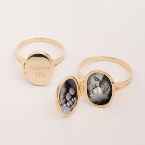 May include: Gold locket ring with a hinged lid. The locket is engraved with the words "Forever Lily". The ring is open and shows a black and white photo of a man holding a baby.