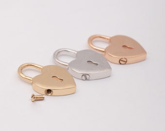 May include: Three heart-shaped padlocks in gold, silver, and rose gold. The padlocks are small and have a keyhole in the front.