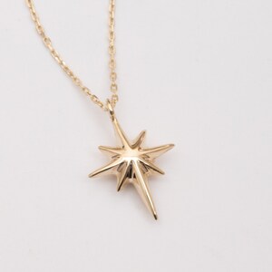 May include: A gold necklace with a star-shaped pendant. The star has a pointed design and is made of solid gold.