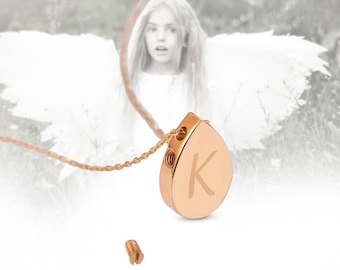 May include: A gold-tone teardrop-shaped pendant necklace with a screw-on top. The pendant has the letter "K" engraved on the front. The necklace is shown with a separate screw.