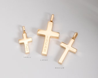 May include: Three gold cross pendants of different sizes. The smallest cross is engraved with the word "Papa", the medium cross is engraved with the date "09.15.2021", and the largest cross is engraved with the name "Lucas".