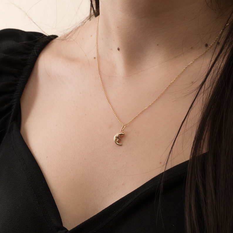 May include: A gold chain necklace with a crescent moon pendant.