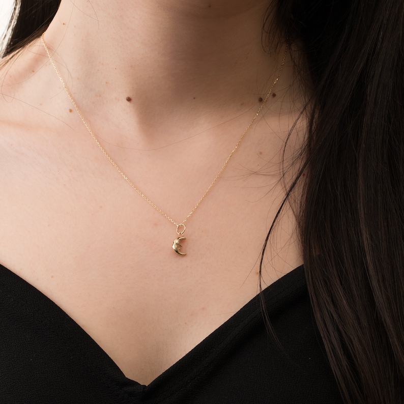 May include: A gold chain necklace with a crescent moon pendant.