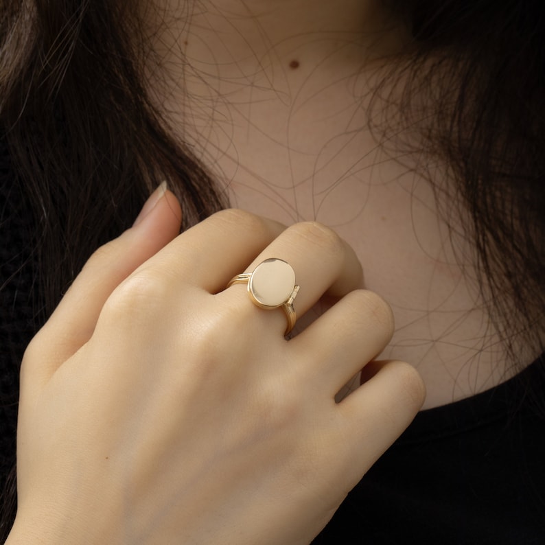 May include: A gold ring with a large, round, smooth, white stone.