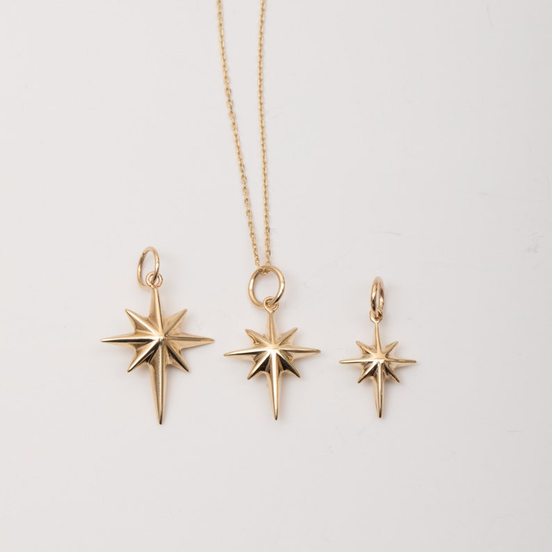 May include: Three gold star-shaped pendants of different sizes. The largest pendant is on a gold chain.