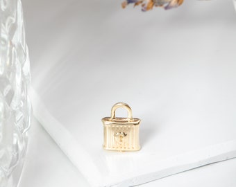 May include: A gold-colored padlock charm with a heart-shaped keyhole. The charm is small and delicate, perfect for adding a touch of whimsy to jewelry or crafts.