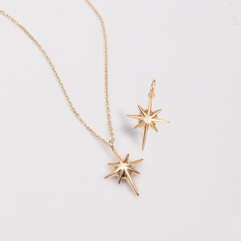 May include: Two gold star-shaped pendants on delicate chains. The larger pendant is on a necklace, while the smaller pendant is on a separate chain.