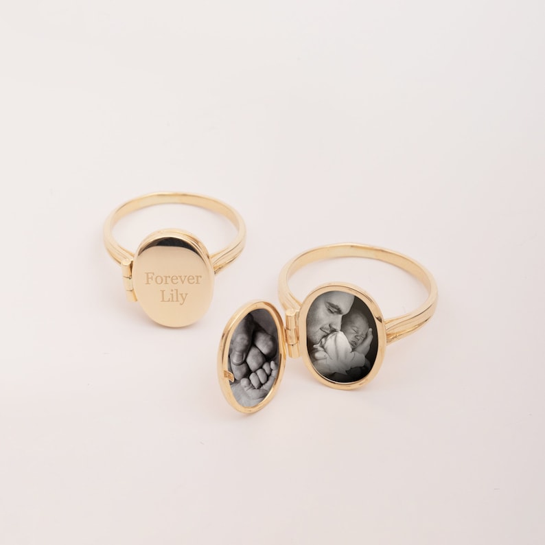 May include: Gold locket ring with a hinged lid. The locket is engraved with the words "Forever Lily". The ring is open and shows a black and white photo of a man holding a baby.