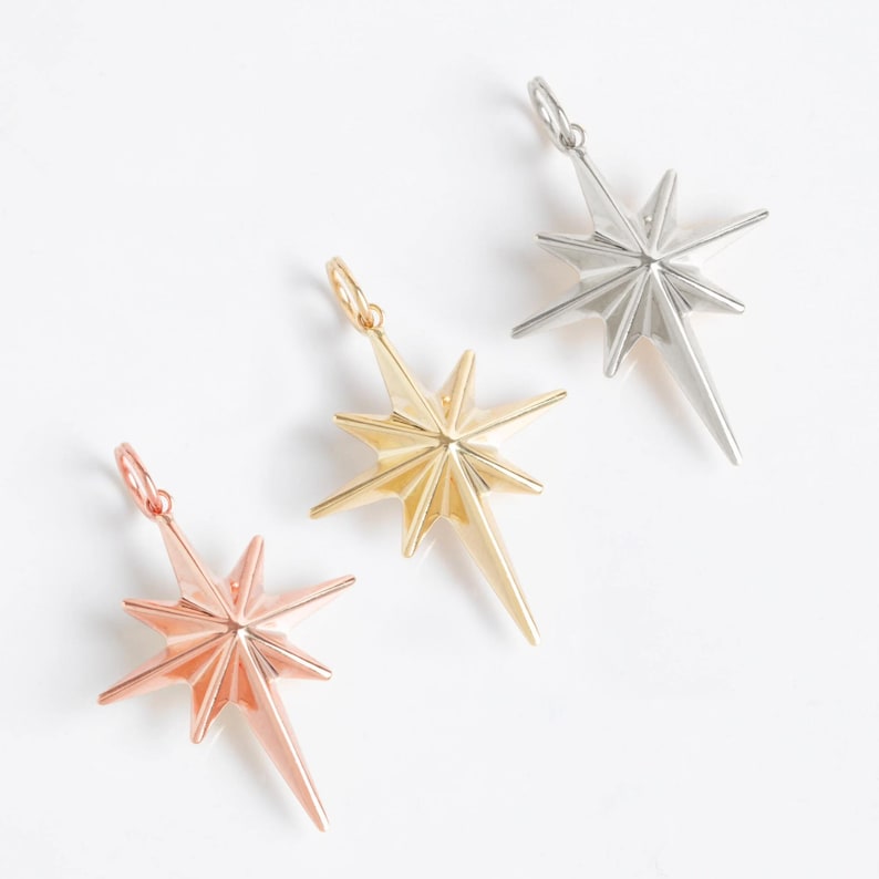 May include: Three star-shaped pendants in different metal finishes: silver, gold, and rose gold. Each pendant features a pointed star design with a raised center.