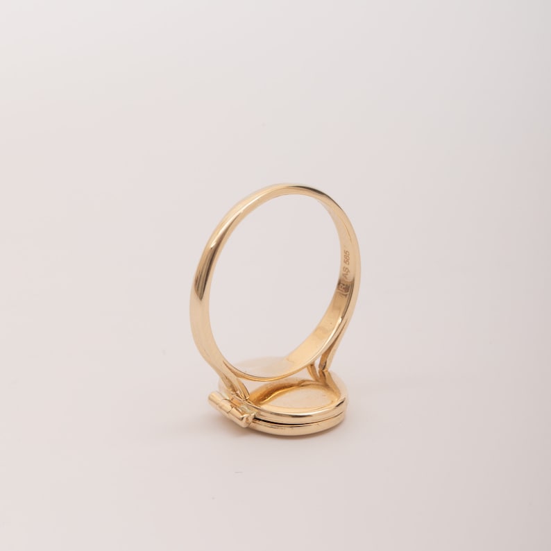 May include: A gold locket ring with a hinged oval locket. The ring is marked with the number "585".
