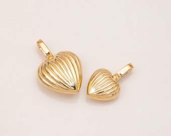 May include: Two gold-colored heart-shaped pendants. The pendants have a ribbed texture and a loop at the top for a chain. The larger pendant is approximately 1 inch wide, and the smaller one is about 0.75 inches wide. Jewelry.