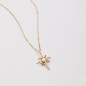 May include: A gold chain necklace with a star-shaped pendant.