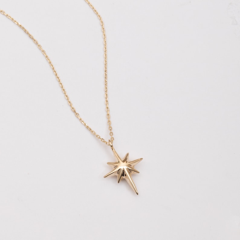 May include: A gold chain necklace with a star-shaped pendant.