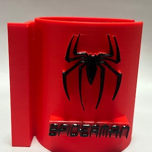 May include: A red plastic cup holder with a black spider-man logo and the word "SPIDERMAN" printed on the front.