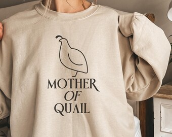 Könnte beinhalten: Ein beiger Pullover mit einer schwarzen Umrandung einer Wachtel und dem Text "Mother of Quail".