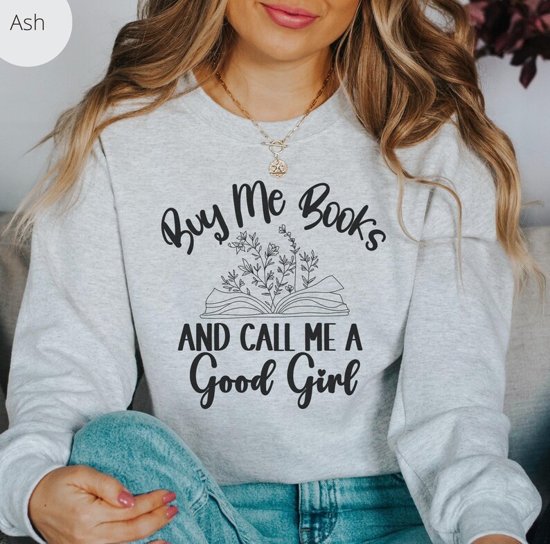 May include: A gray sweatshirt with the text "Buy Me Books and Call Me a Good Girl" printed on it. The text is surrounded by a drawing of an open book with flowers.