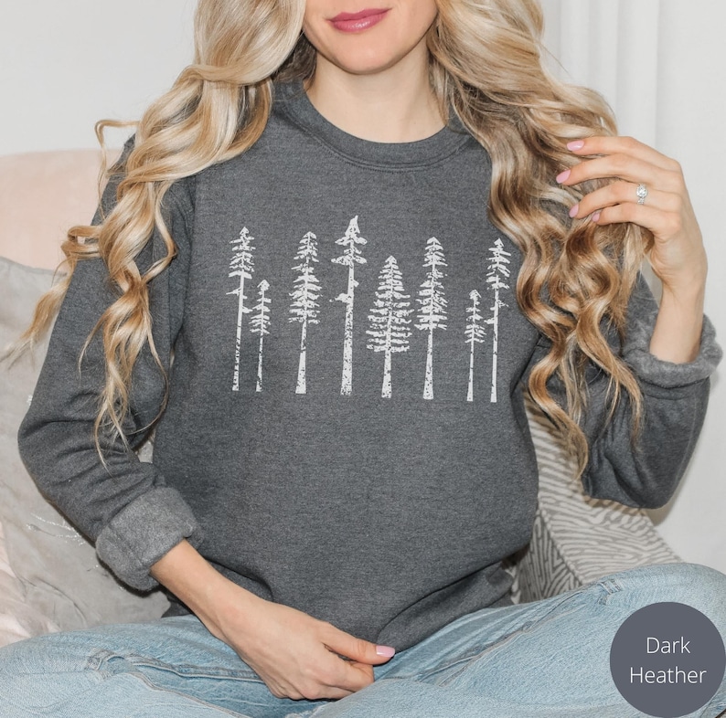 May include: A dark heather grey sweatshirt with a white graphic of a row of stylized trees.