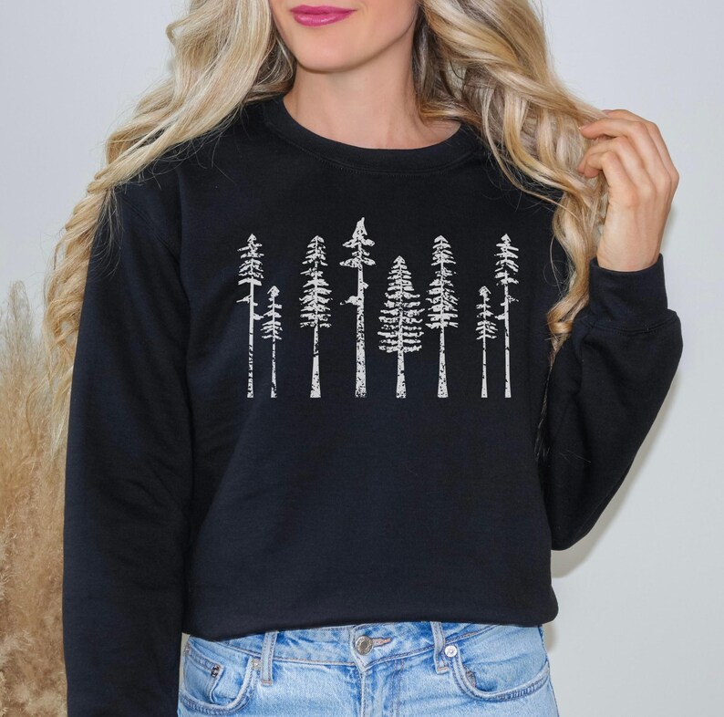 May include: Black sweatshirt with a white graphic print of a row of stylized trees.