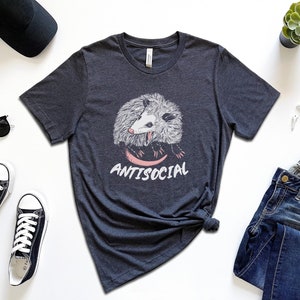 May include: A heather navy t-shirt with a graphic of a possum and the text "ANTISOCIAL".