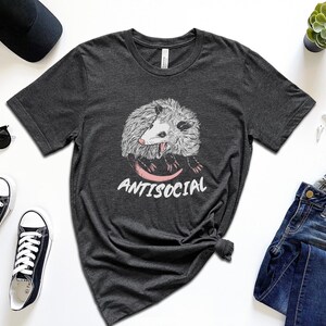 May include: Dark grey heather t-shirt with a graphic of a possum and the text "Antisocial".