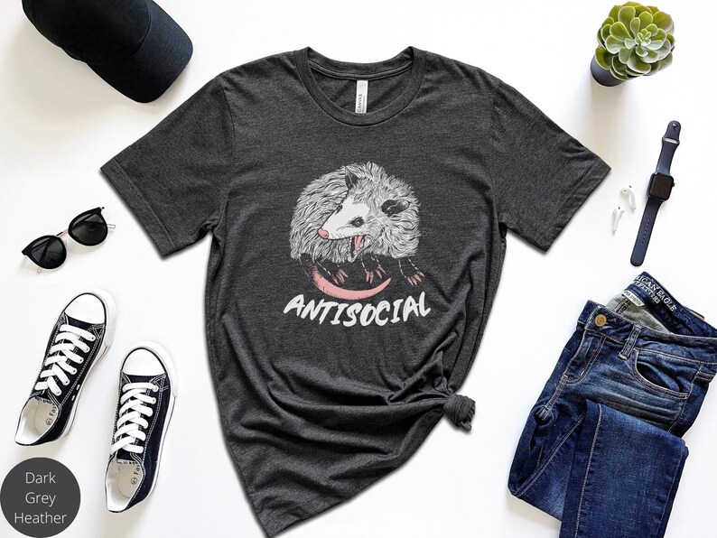 May include: Dark grey heather t-shirt with a graphic of a possum and the text "Antisocial".