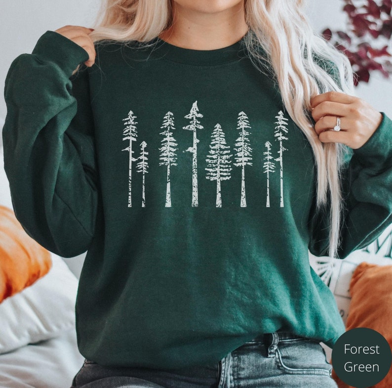 May include: A forest green sweatshirt with a white graphic print of a row of stylized trees.