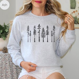 May include: A gray sweatshirt with a black print of a row of trees. The trees are stylized and have a distressed look.