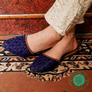 May include: Blue embroidered slip-on shoes with brown trim, featuring a floral pattern. The shoes are displayed on a patterned rug. The text "Shoe Jewel Art" is in a green circle in the bottom right corner.