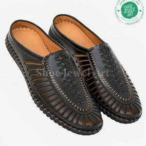 May include: A pair of black leather slip-on shoes with a woven design on the top and cut-out details. The shoes have a brown leather insole and a stitched border. The image includes a logo that says "Shoe Jewel Art Premium Shoes".