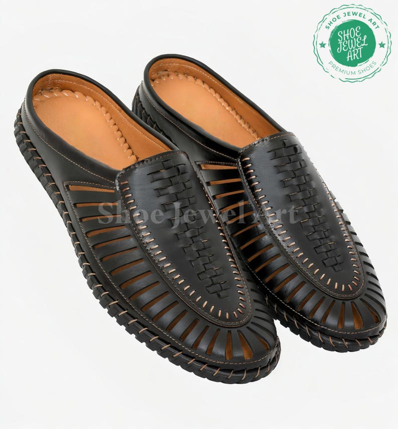 May include: A pair of black leather slip-on shoes with a woven design on the top and cut-out details. The shoes have a brown leather insole and a stitched border. The image includes a logo that says "Shoe Jewel Art Premium Shoes".