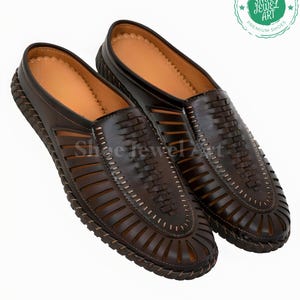 May include: A pair of brown leather slip-on shoes with intricate woven and cut-out designs. The shoes have a light brown interior and a stitched, textured sole. The image includes a logo that says "Shoe Jewel Art Premium Shoes".