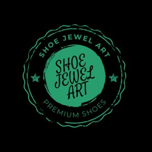 May include: A circular logo with the text "SHOE JEWEL ART" in a green, distressed font. The logo is set against a black background and includes the words "PREMIUM SHOES". Two small stars flank the central text.