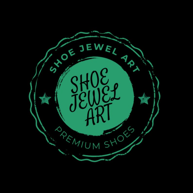 May include: A circular logo with the text "SHOE JEWEL ART" in a green, distressed font. The logo is set against a black background and includes the words "PREMIUM SHOES". Two small stars flank the central text.