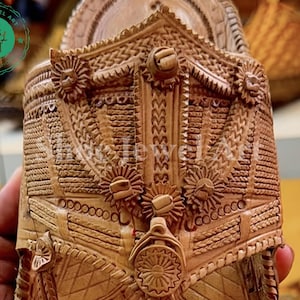 May include: Close-up of a carved wooden object with intricate floral and geometric patterns. The object is a light brown color and features detailed relief work, including circular and star-like designs. The image is well-lit, highlighting the texture and craftsmanship.
