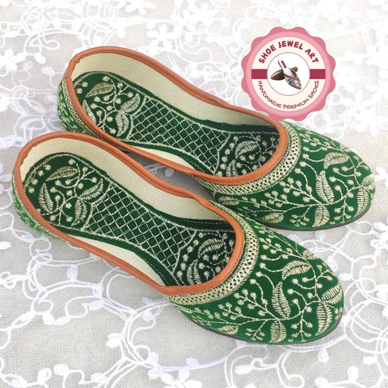 K&ouml;nnte beinhalten: Ein Paar gr&uuml;n-gold bestickte Ballerinas. Die Schuhe weisen aufwendige Blumen- und geometrische Muster auf, mit einem cremefarbenen Innenraum und einer braunen Umrandung. Handgefertigte Premium-Schuhe.