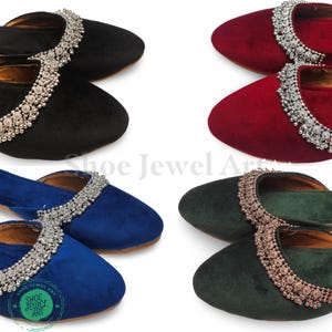 May include: Four pairs of velvet slip-on shoes in black, red, blue, and green. Each shoe features a decorative silver-colored trim along the top edge. The shoes are displayed on a white background, showcasing their colors and design.
